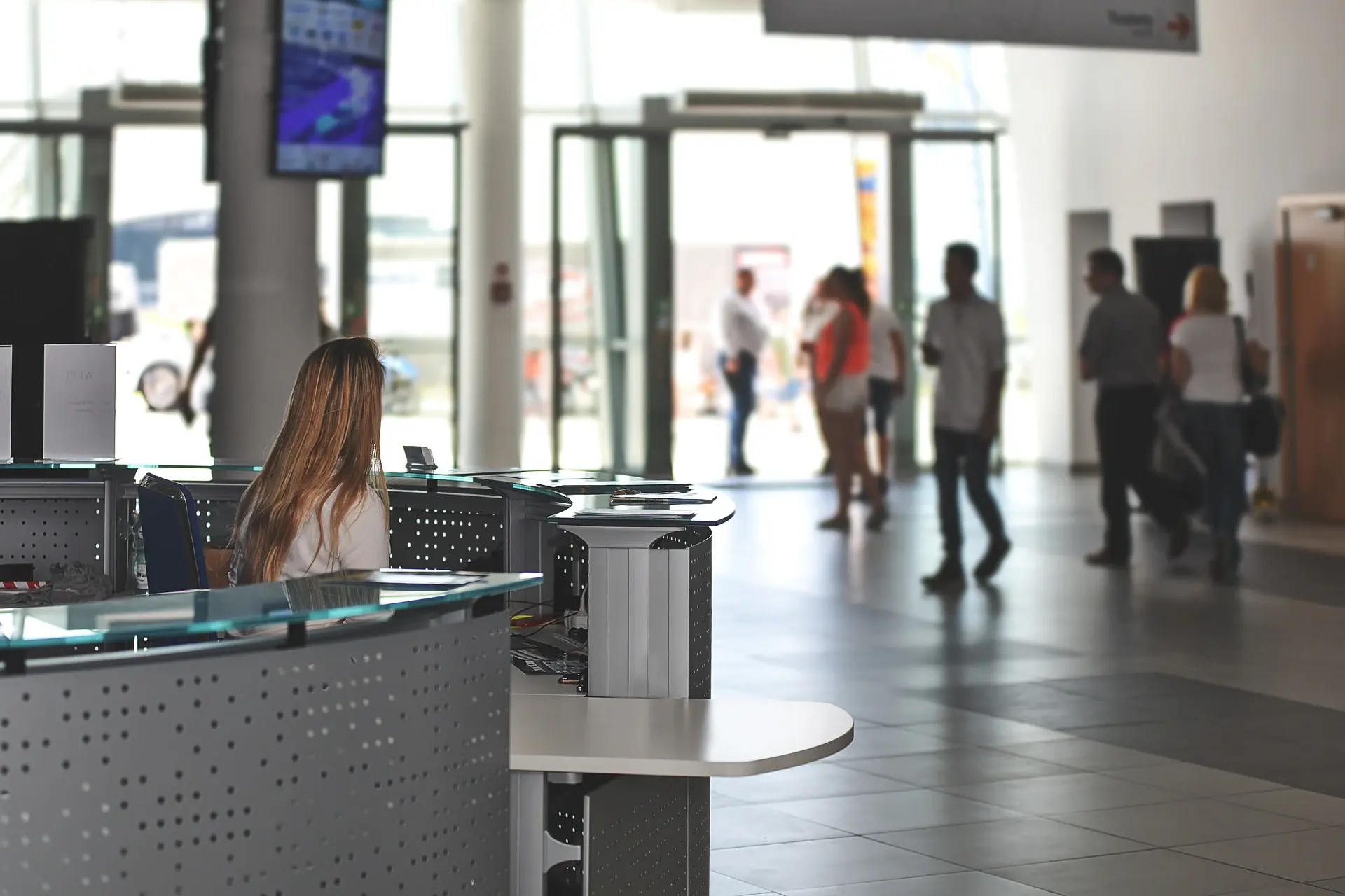 A busy corporate lobby with a reception desk and people walking through